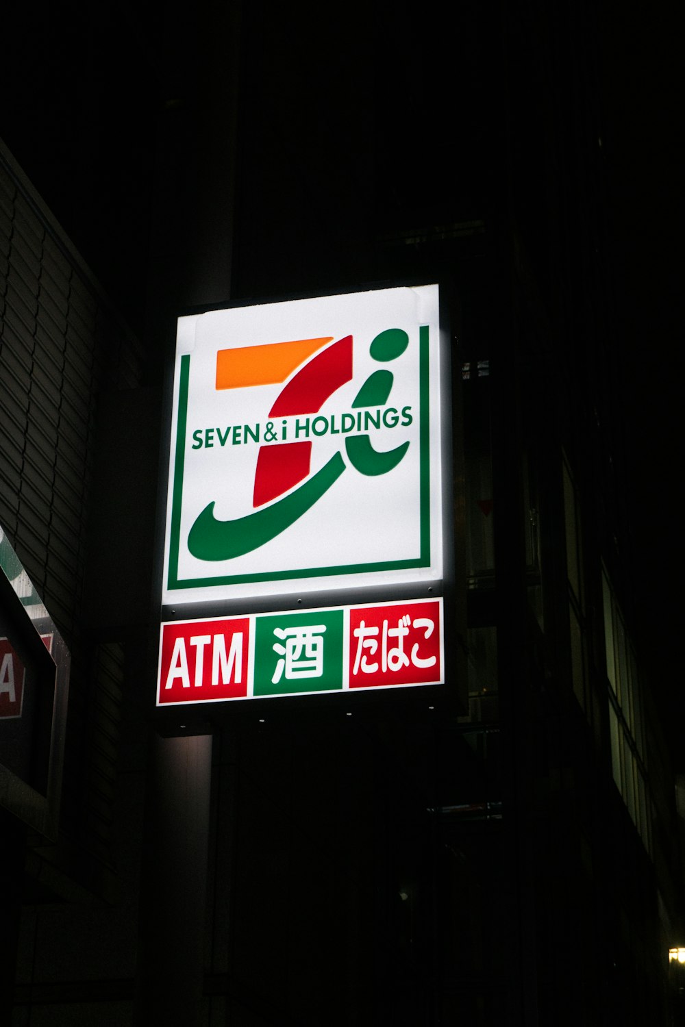 a seven and holdings sign lit up at night