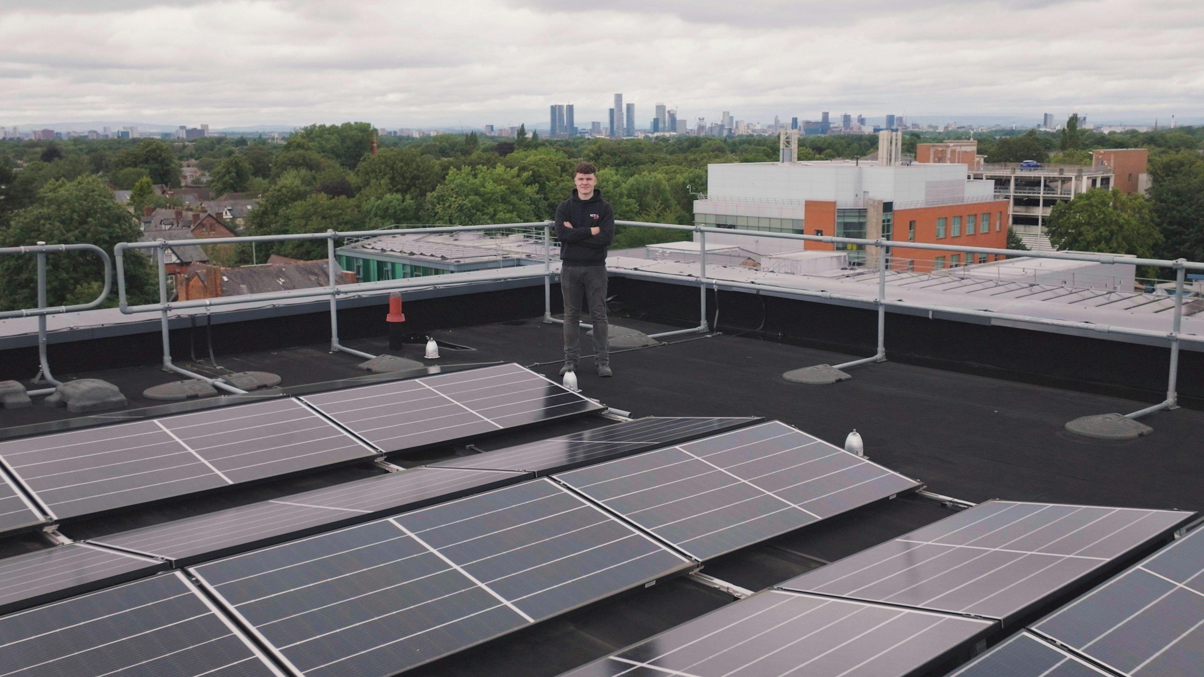 a man standing on top of a roof next to solar panels