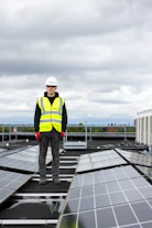 a man standing on top of a roof covered in solar panels
