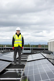 a man standing on top of a roof covered in solar panels