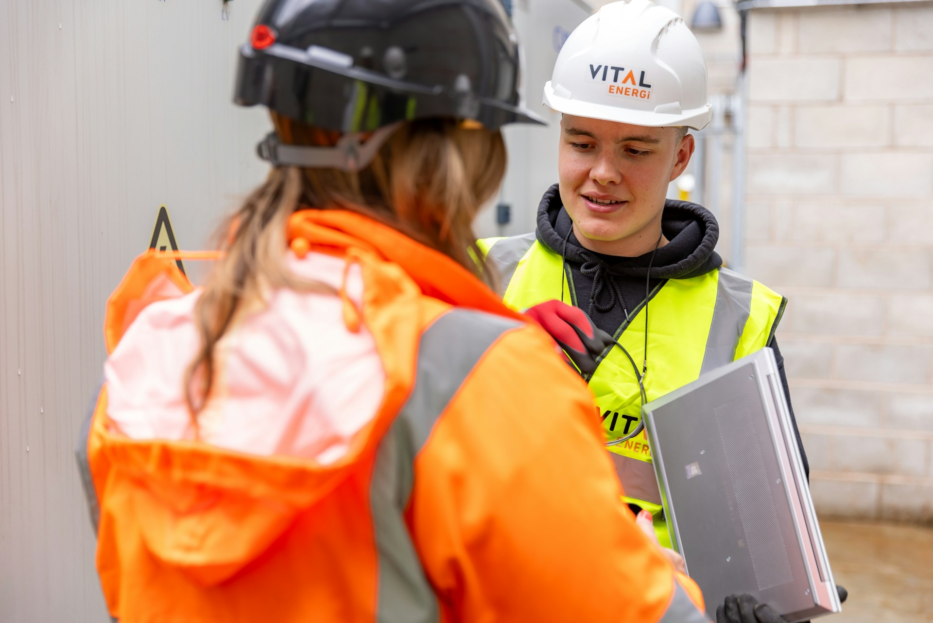a woman in a safety vest talking to a woman in a hard hat