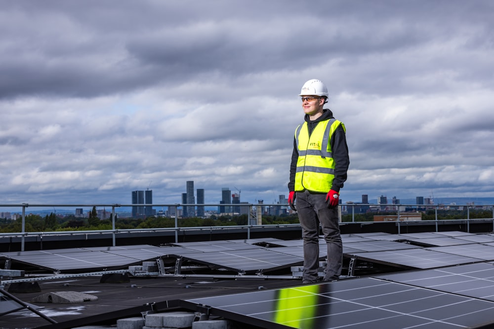 a man standing on top of a roof next to solar panels