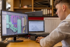 a man sitting at a desk looking at a computer screen