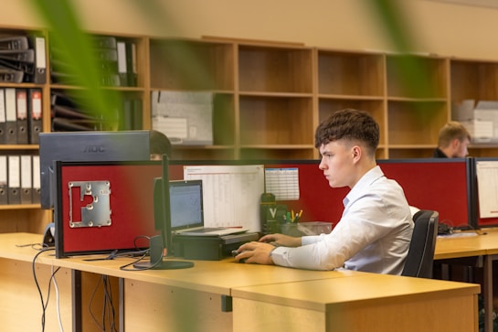 a man sitting at a desk in front of a computer monitor