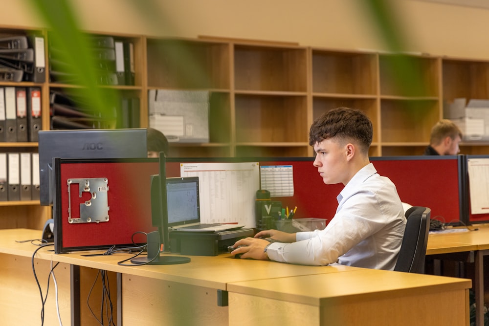 a man sitting at a desk in front of a computer monitor