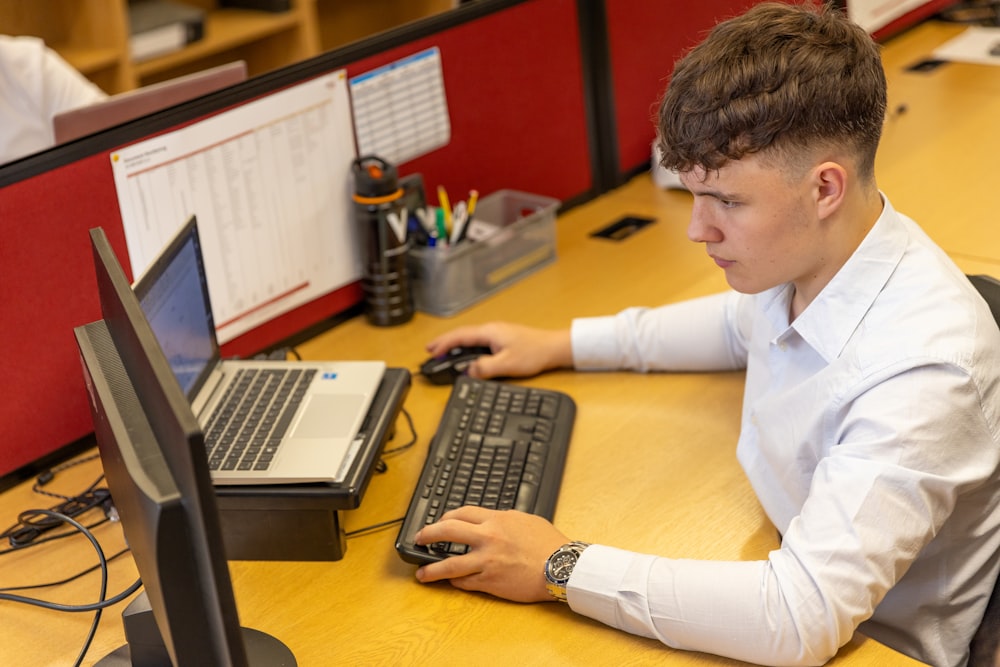 a young man sitting at a desk using a computer