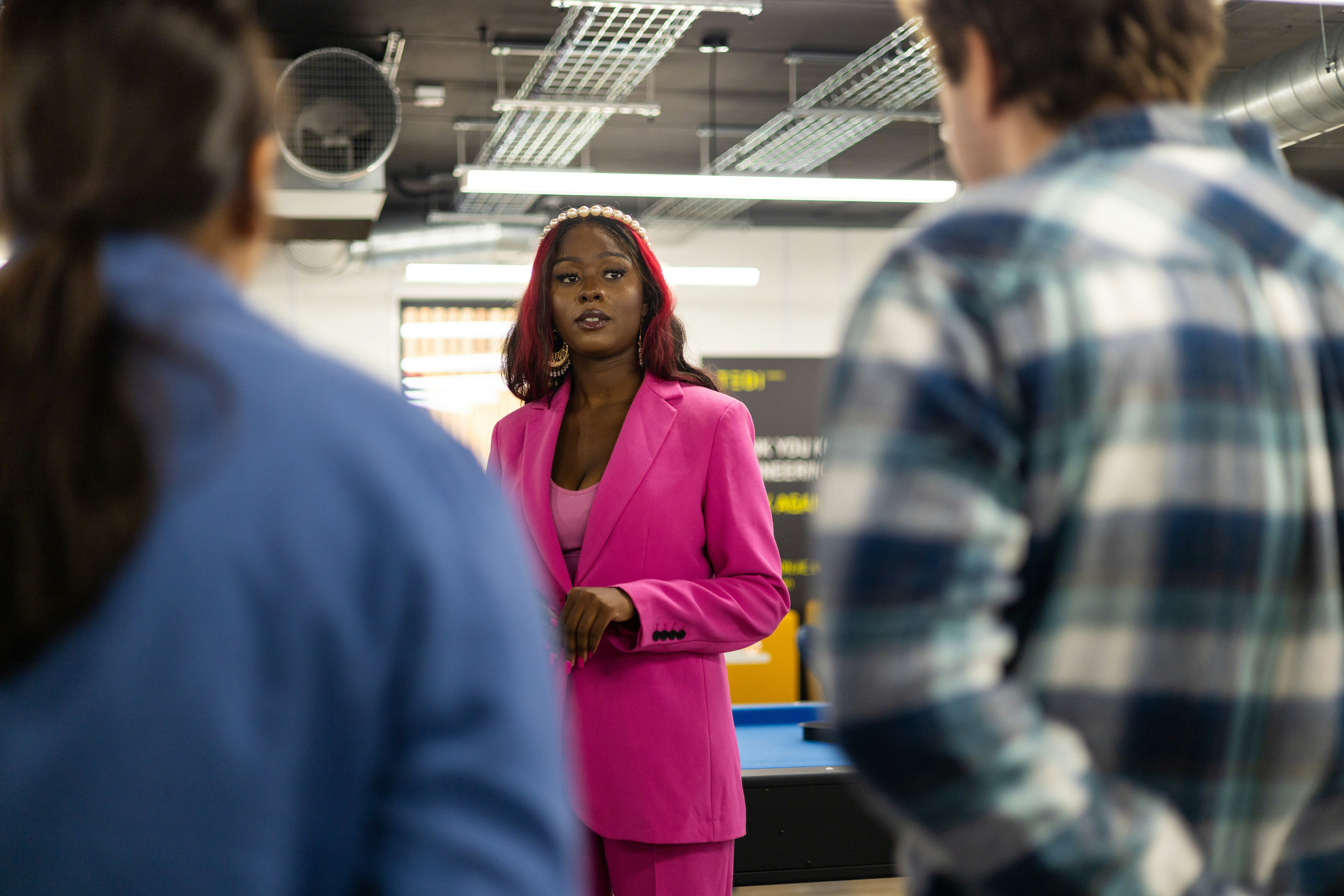 a woman in a pink suit talking to a group of people