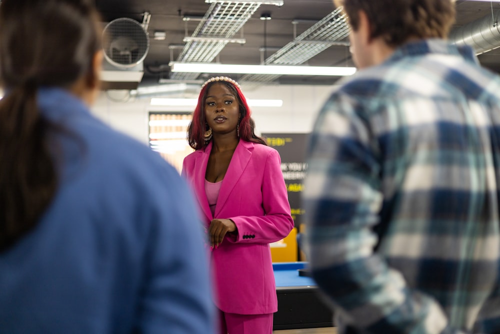 a woman in a pink suit talking to a group of people