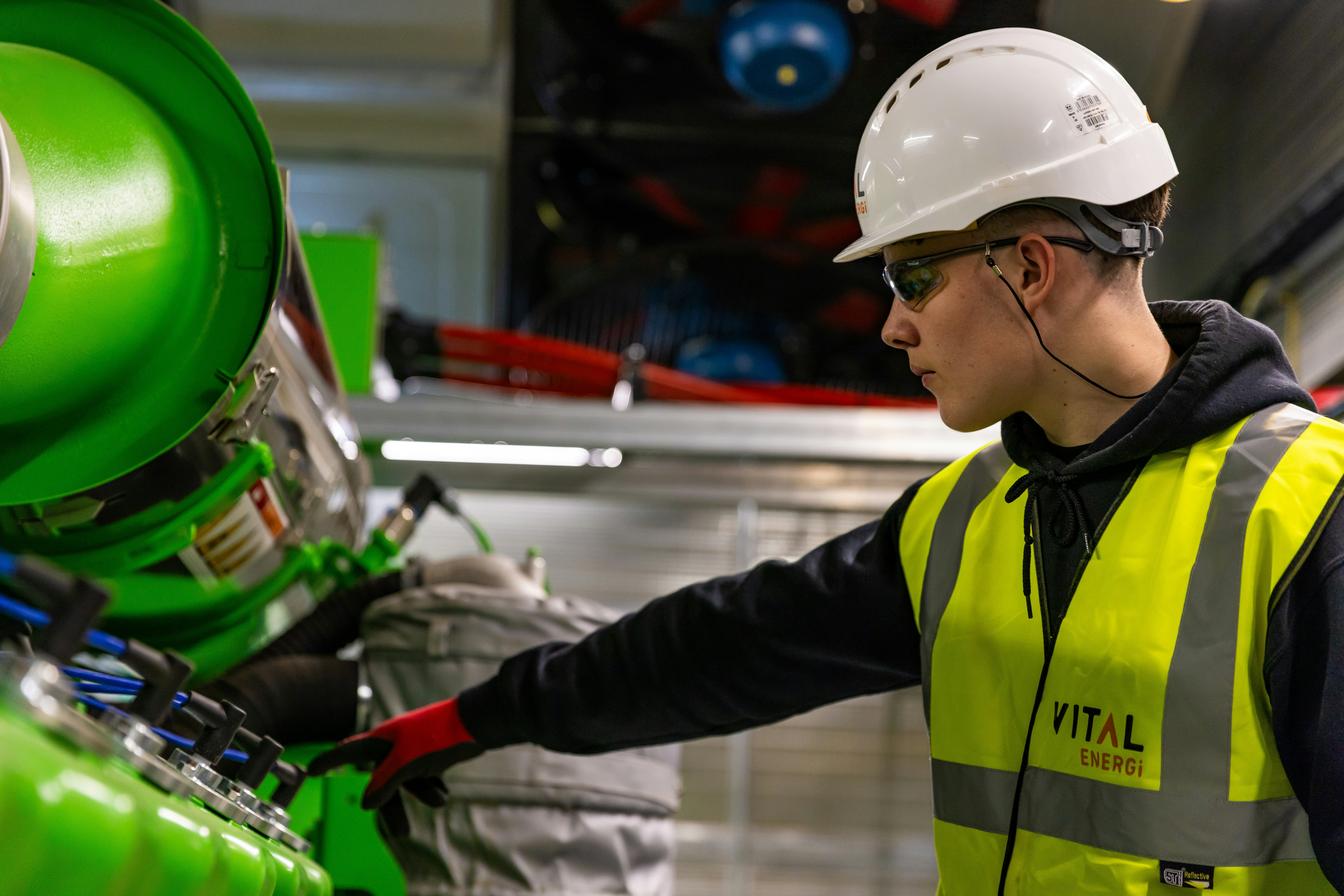 a man in a hard hat and safety vest working on a machine