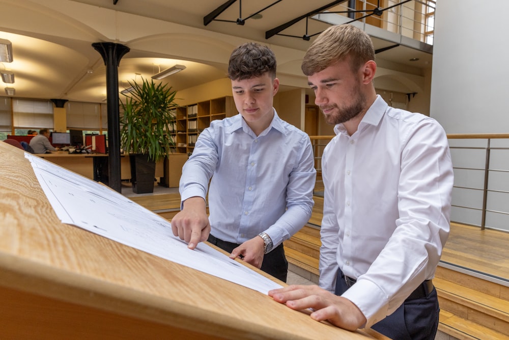 two men looking at a piece of paper on a table