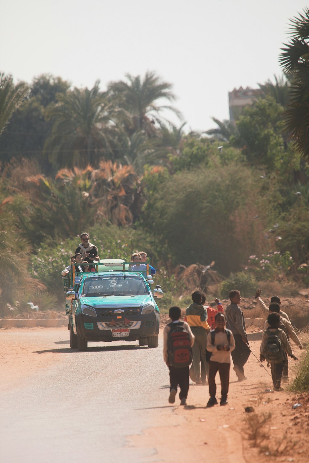 a group of people walking down a dirt road