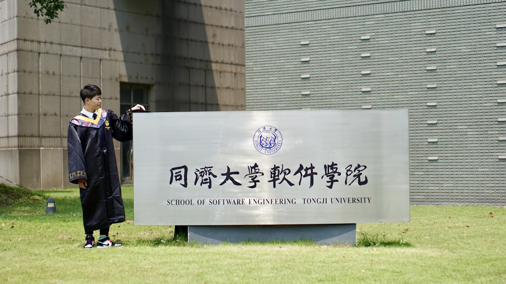 a man standing next to a sign in front of a building