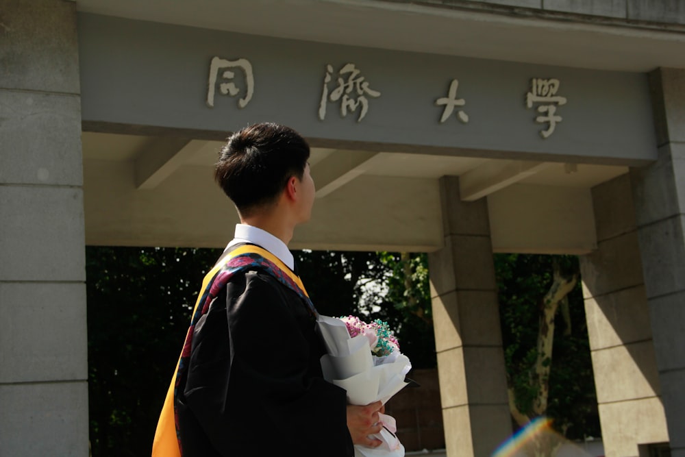 a man holding a bouquet of flowers in front of a building