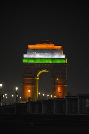a very tall clock tower with a green and white flag on it's side