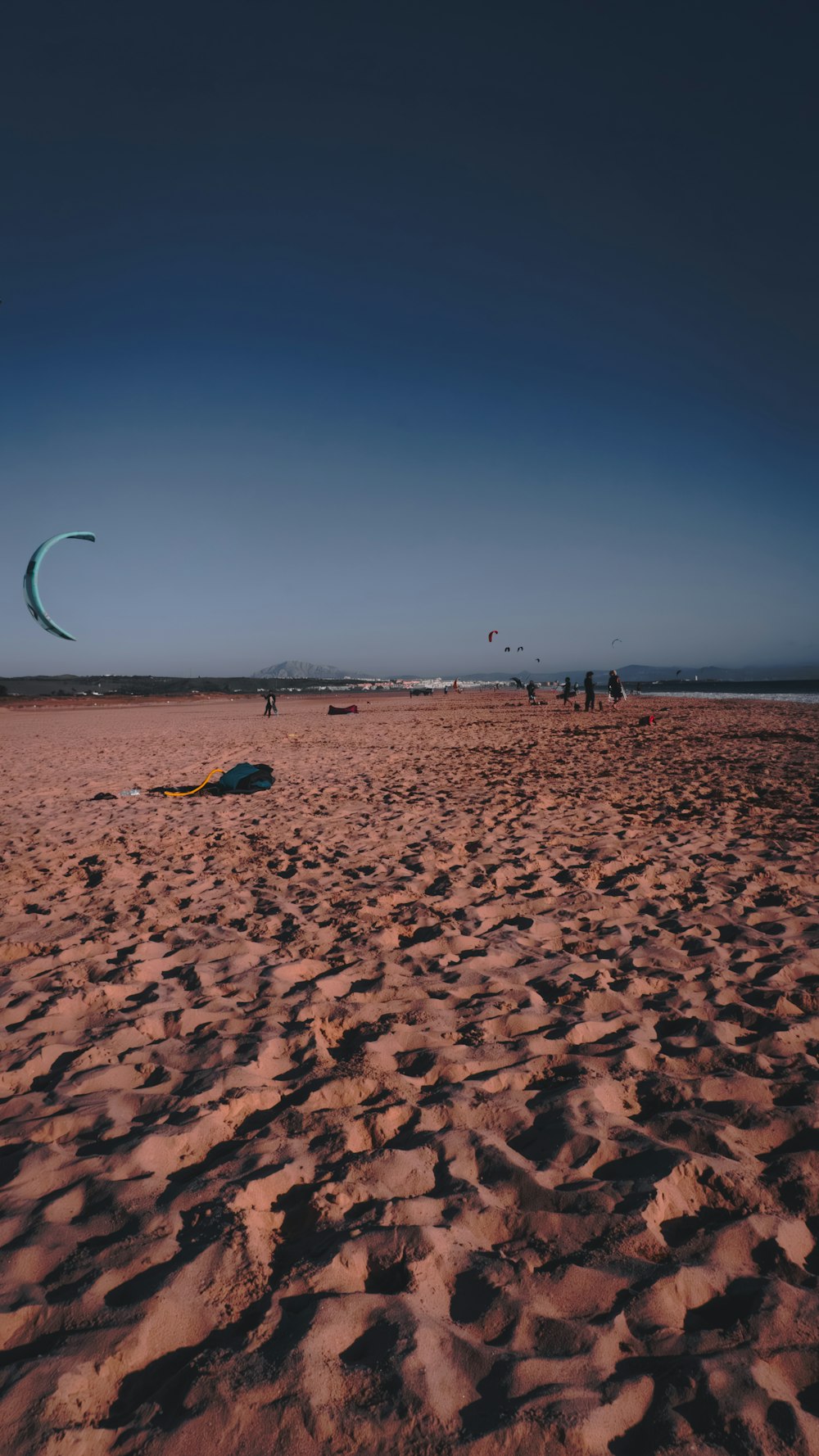 a kite flying over a sandy beach under a blue sky