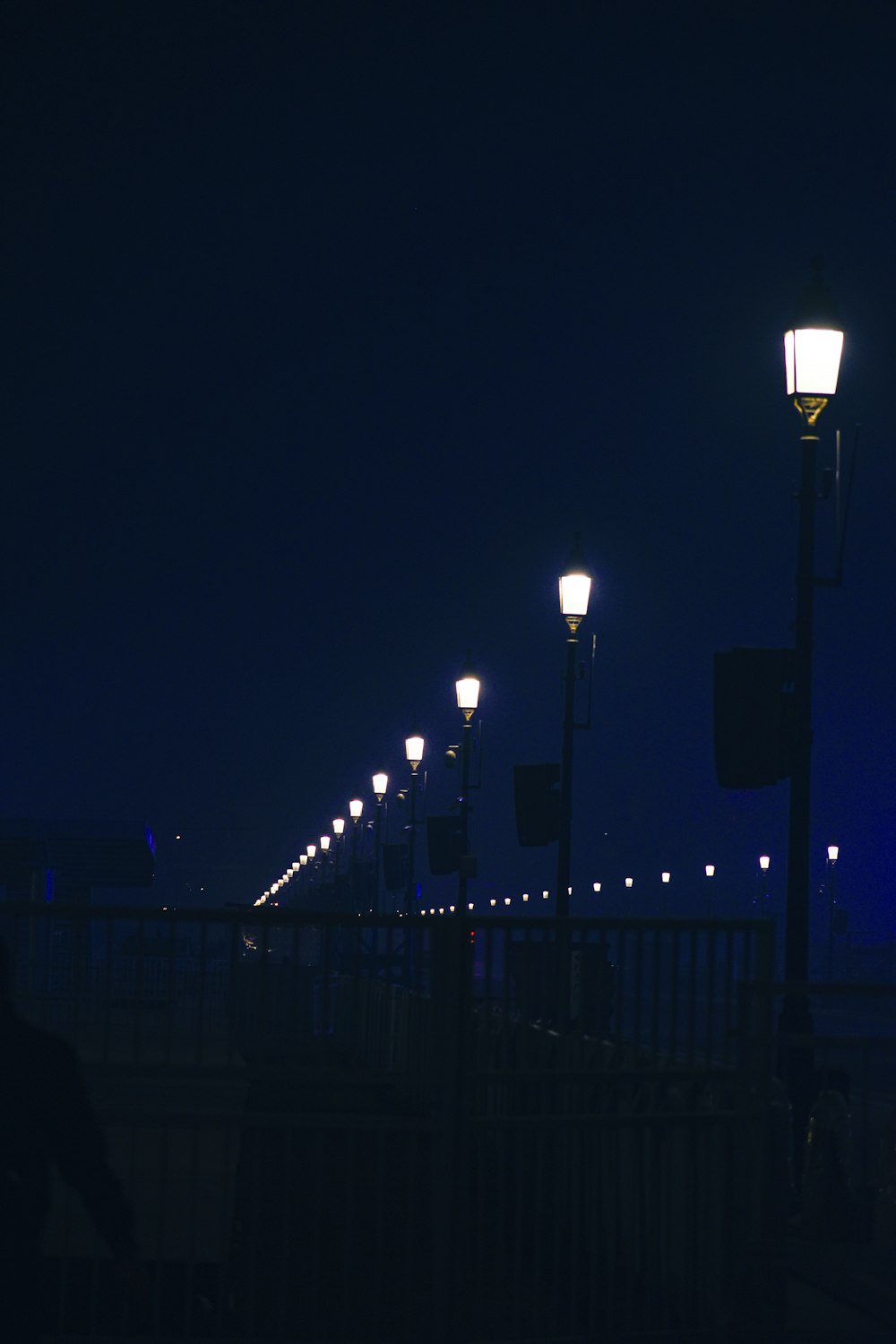 a row of street lights on a bridge at night