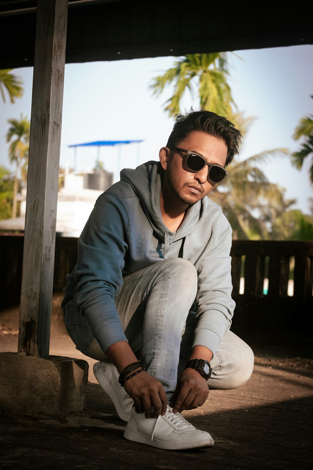 a man in a hoodie and sunglasses sitting on the ground