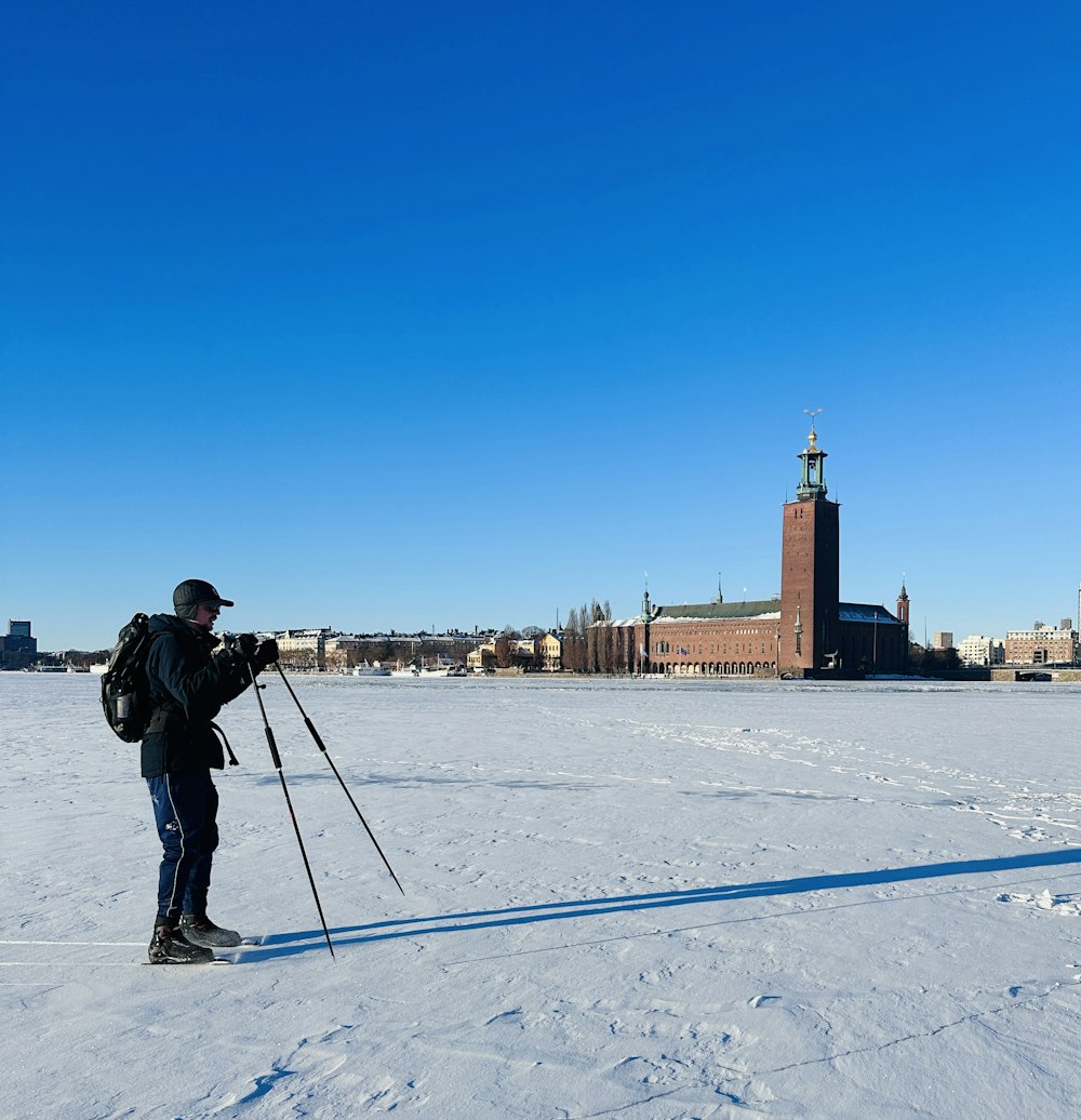 a man with a backpack and skis standing in the snow