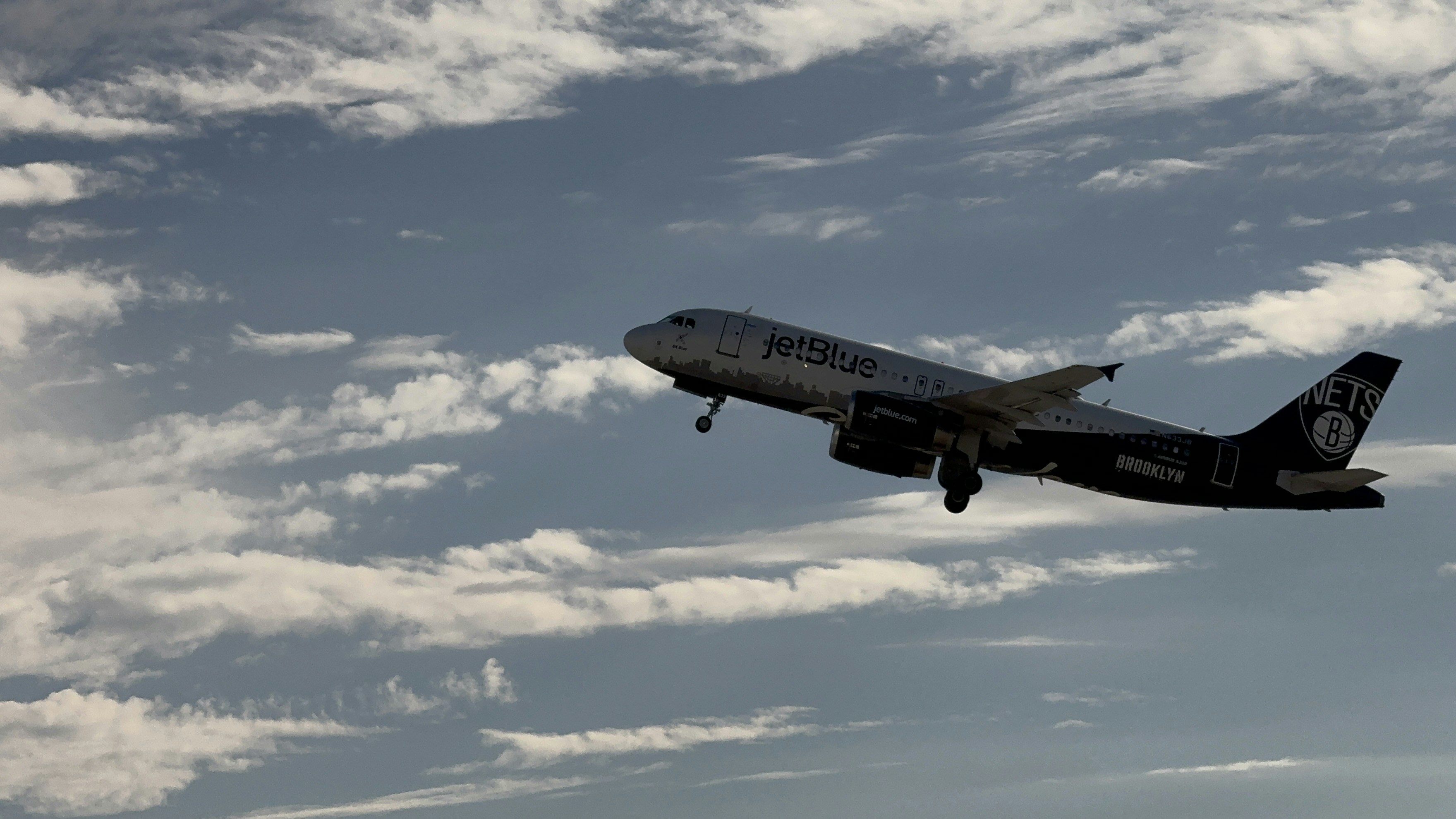 a large jetliner flying through a cloudy blue sky, 