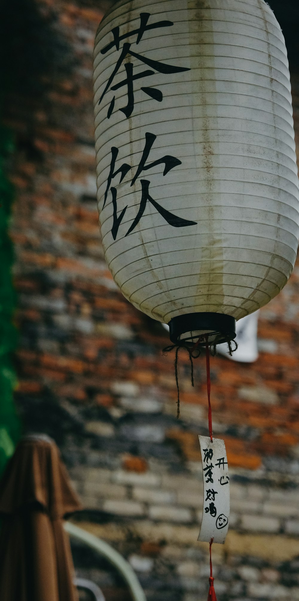 a chinese lantern hanging in front of a brick wall