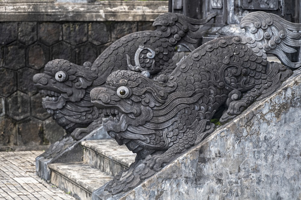 a couple of statues sitting on top of a stone wall