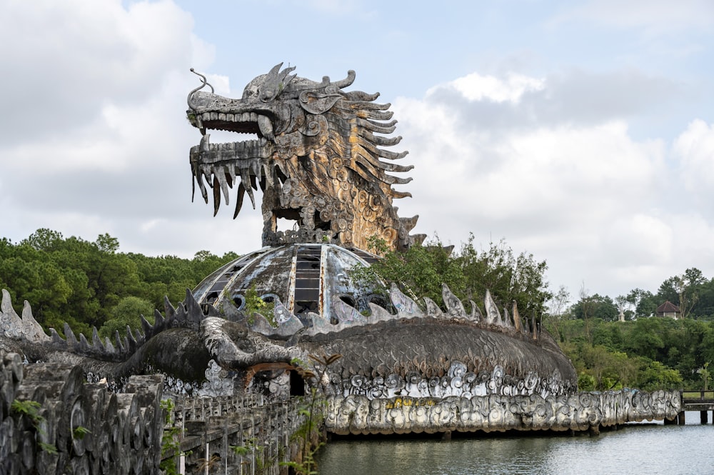 a statue of a dragon on top of a building next to a body of water