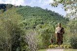 a statue of buddha in the middle of a forest