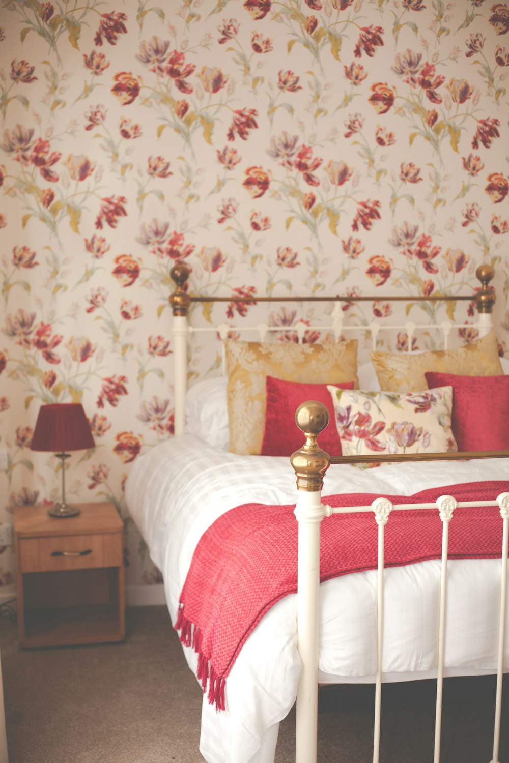 a bed with a red blanket and a white headboard