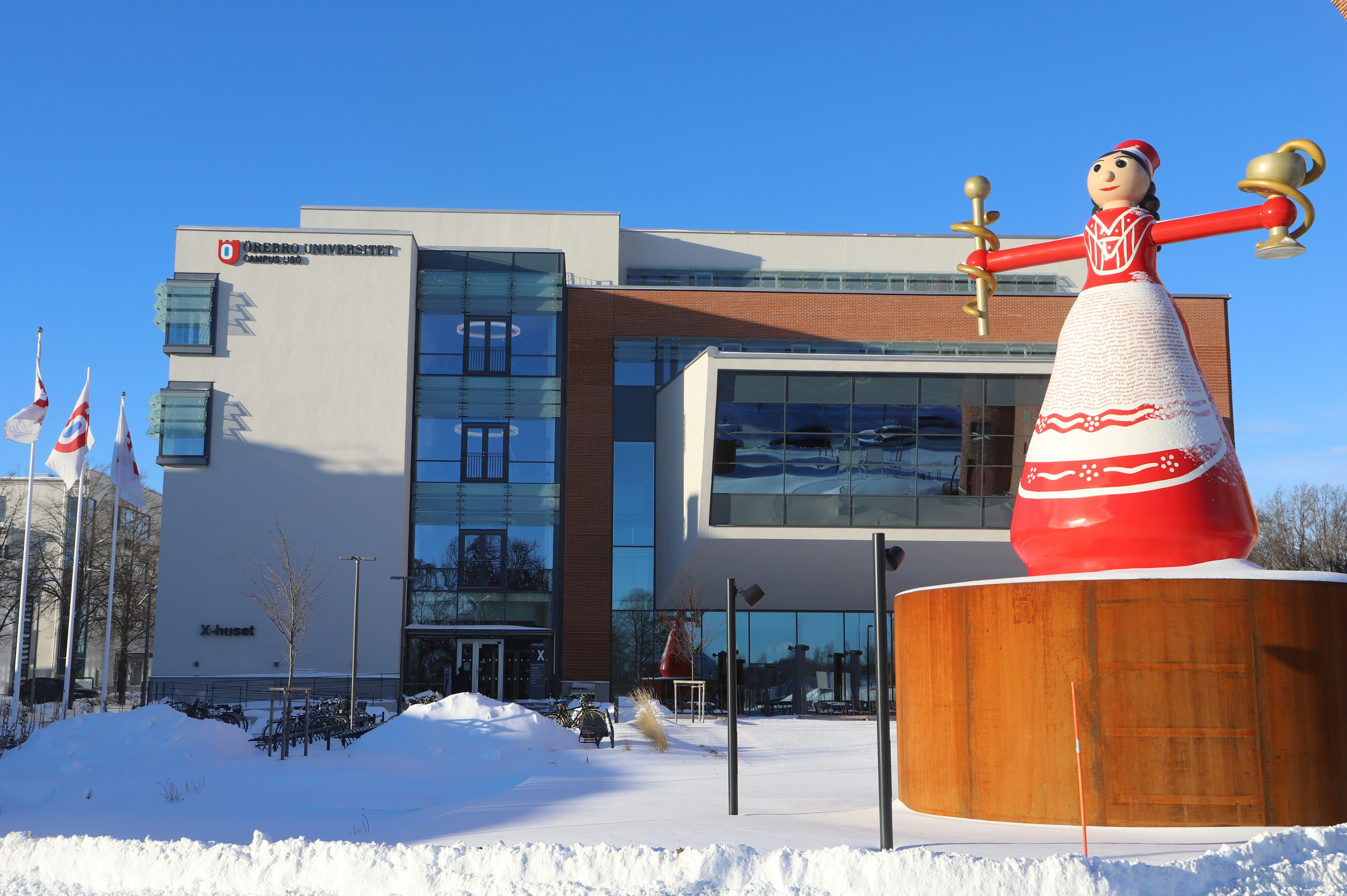 a large statue of a person holding a cup in front of a building