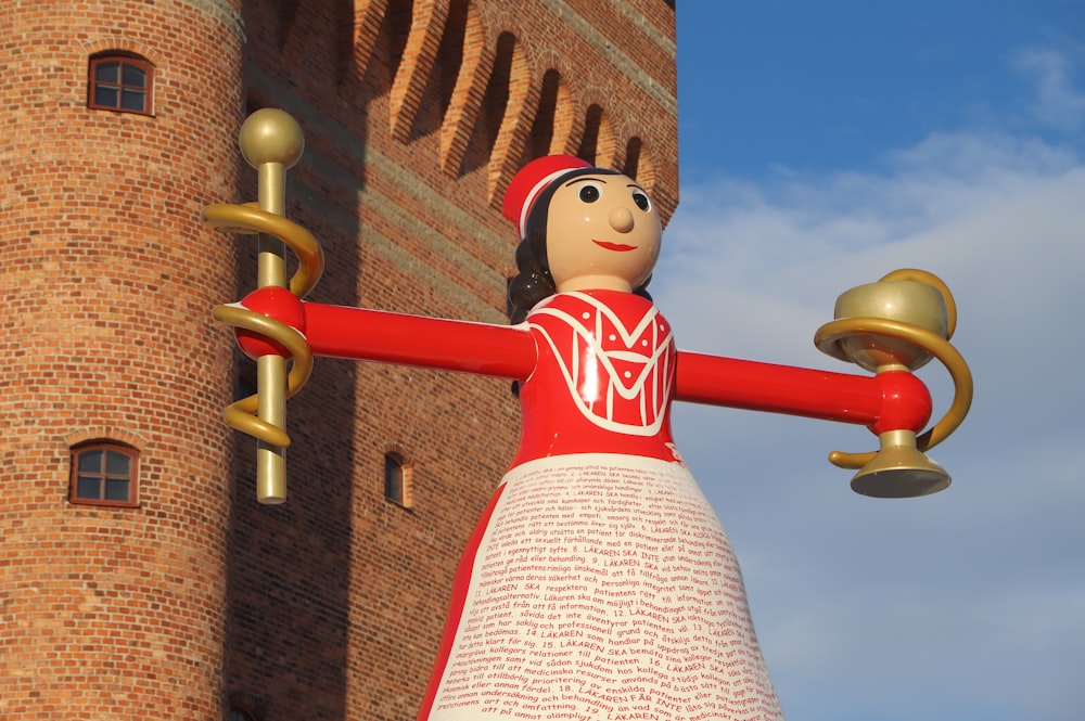a statue of a woman holding a bell in front of a brick building