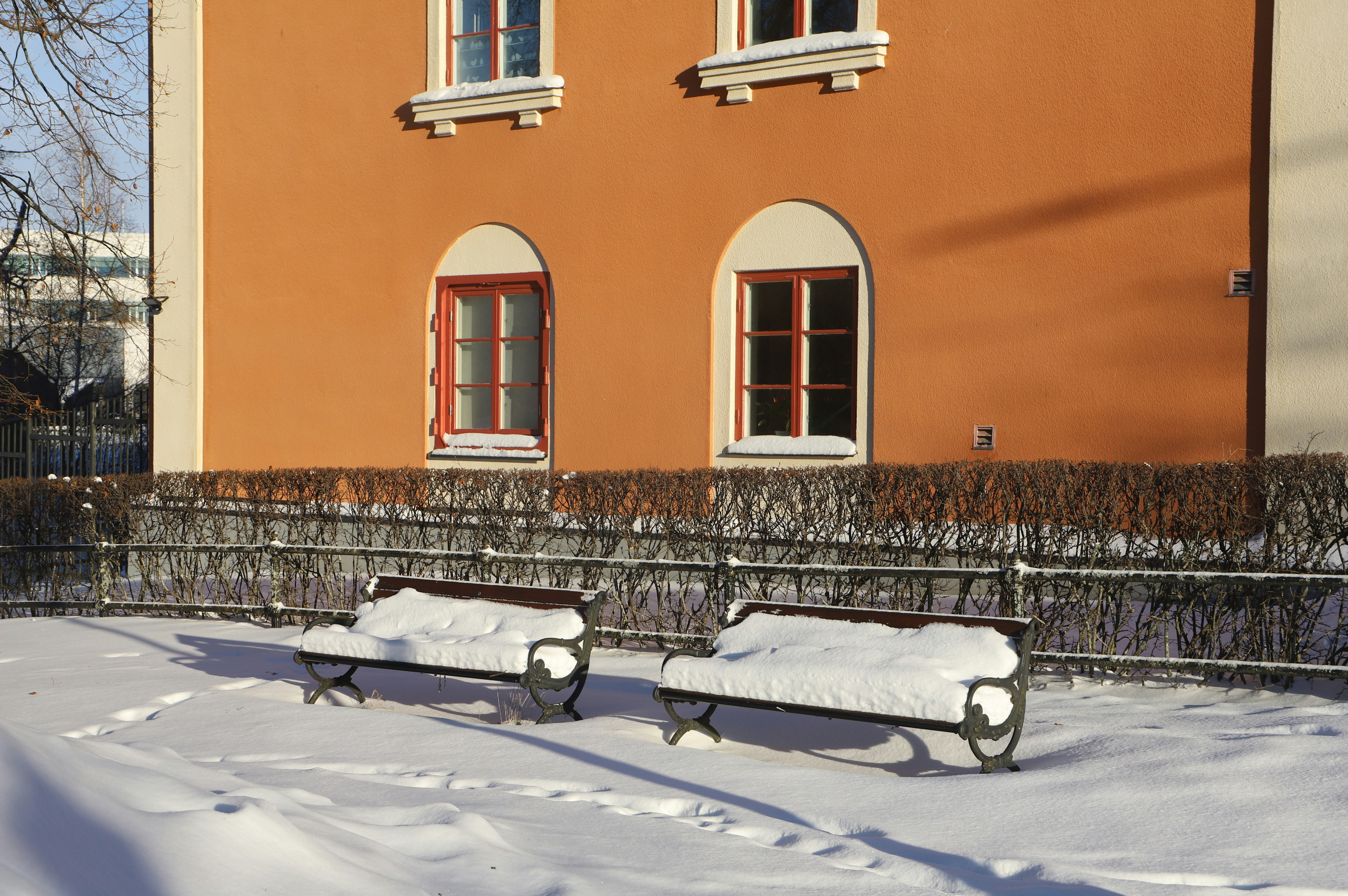 two benches covered in snow in front of a building