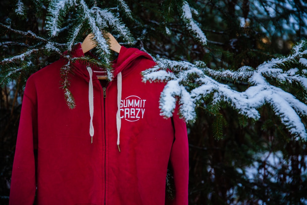 a red sweatshirt with a white logo is hanging on a tree