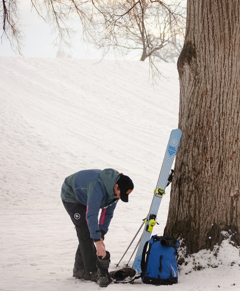 a man standing next to a tree in the snow