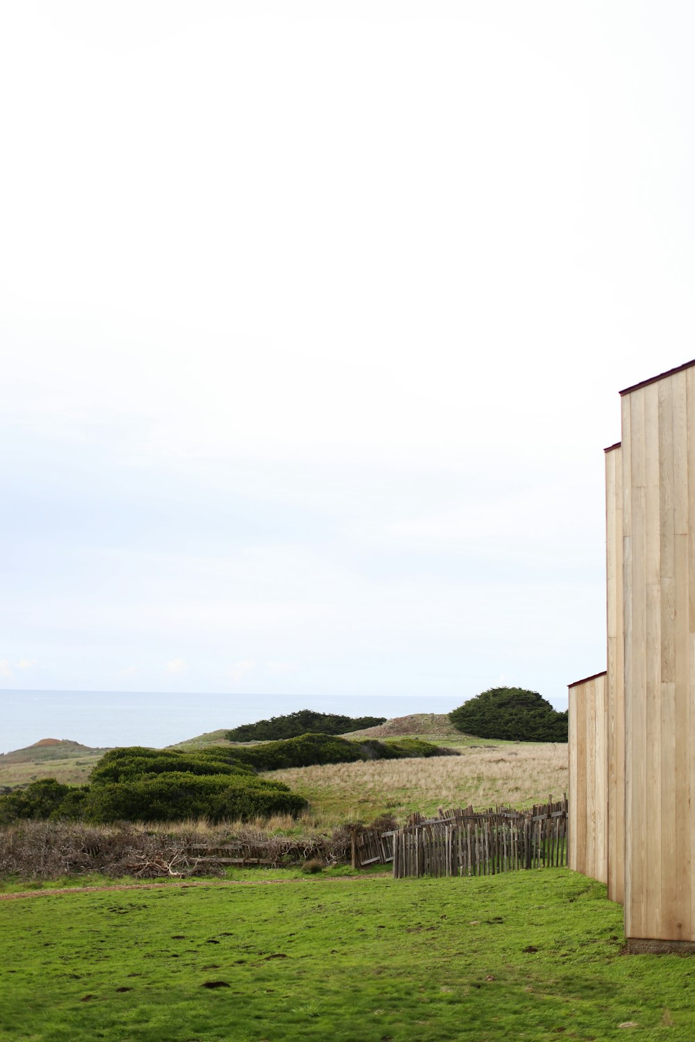 a wooden building sitting on top of a lush green field