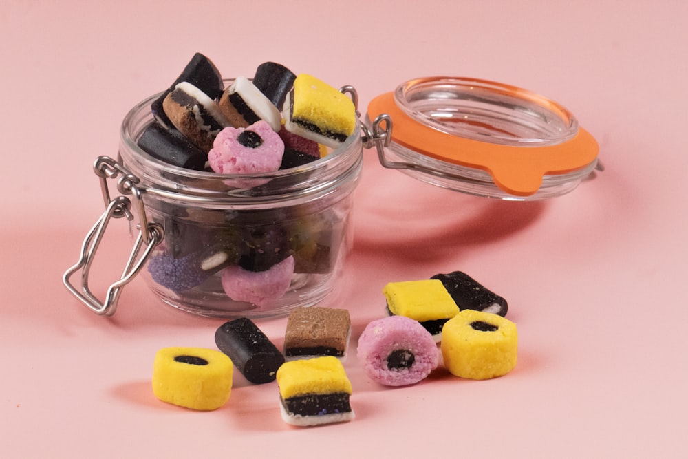 a jar filled with assorted candies next to a pair of scissors