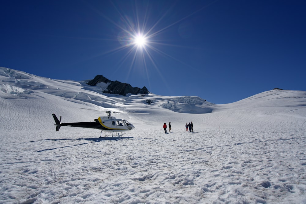 um helicóptero sentado no topo de uma encosta coberta de neve