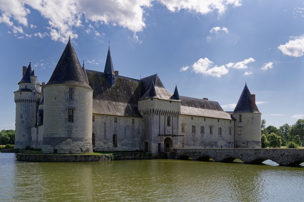 a large castle sitting on top of a lake next to a bridge