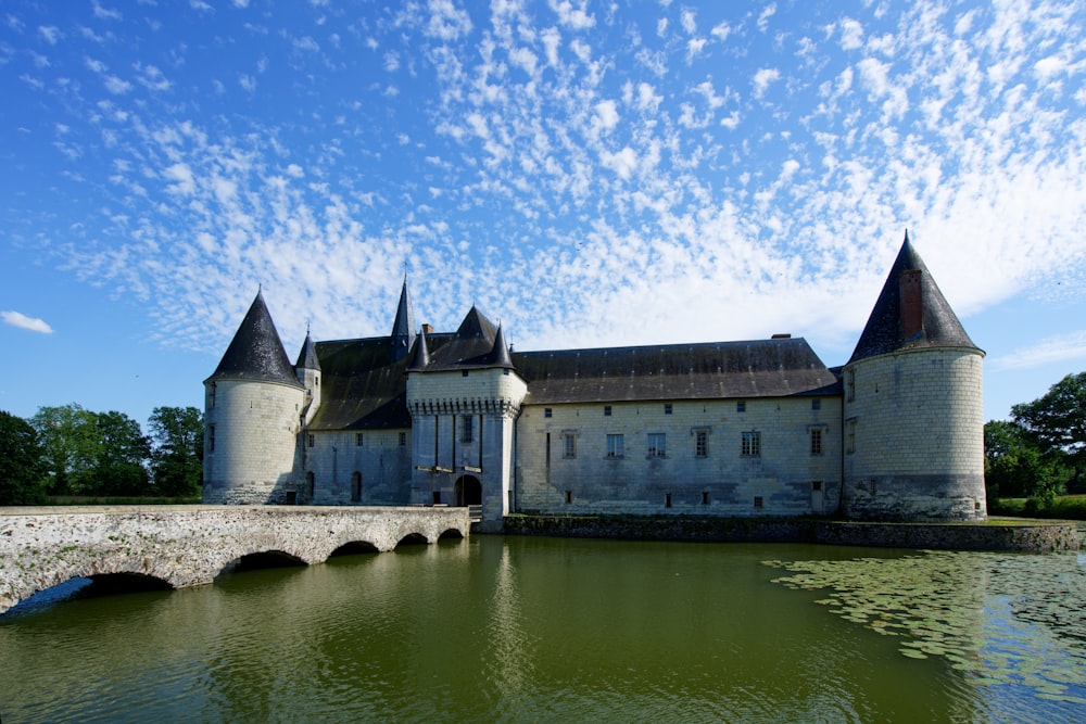 a large castle sitting on top of a lake next to a bridge