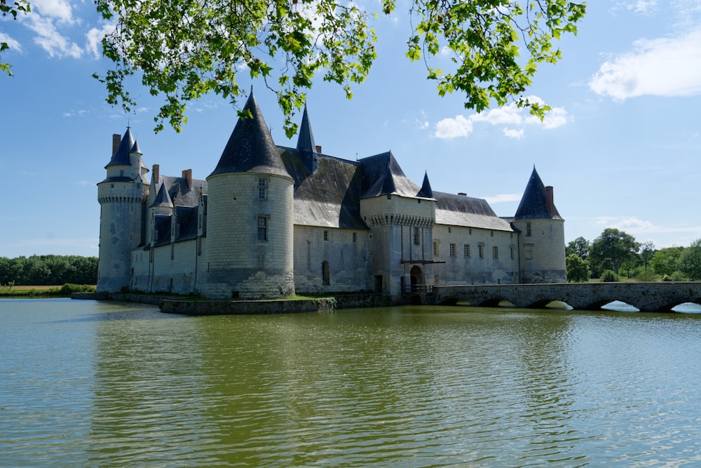 a castle sitting on top of a lake next to a bridge