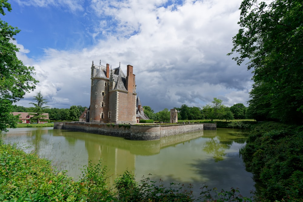 a castle sitting on top of a lake surrounded by trees