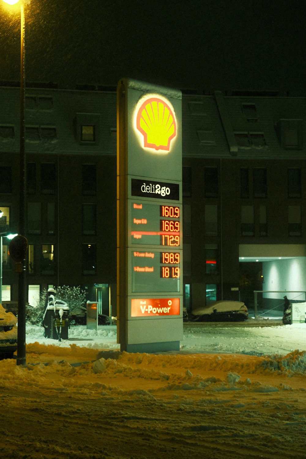a gas station sign in the snow at night