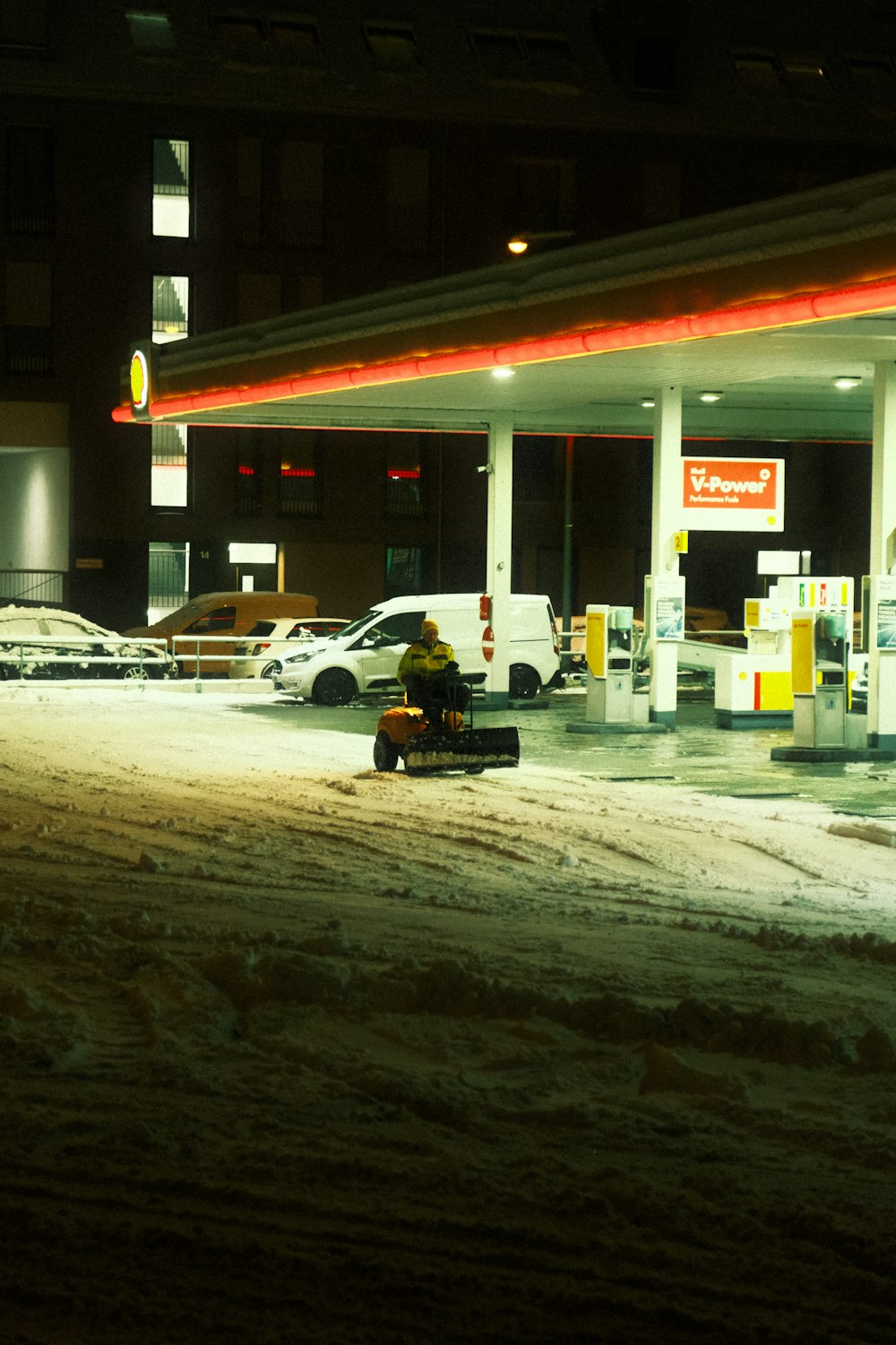 地面に雪が積もる夜のガソリンスタンド