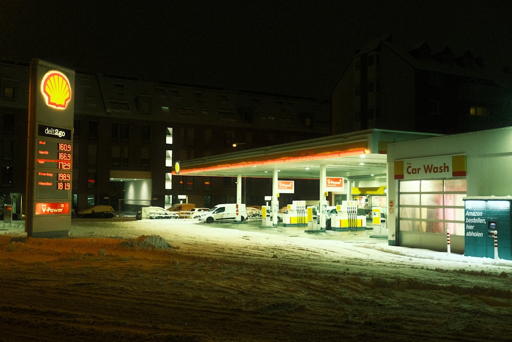 地面に雪が積もる夜のガソリンスタンド