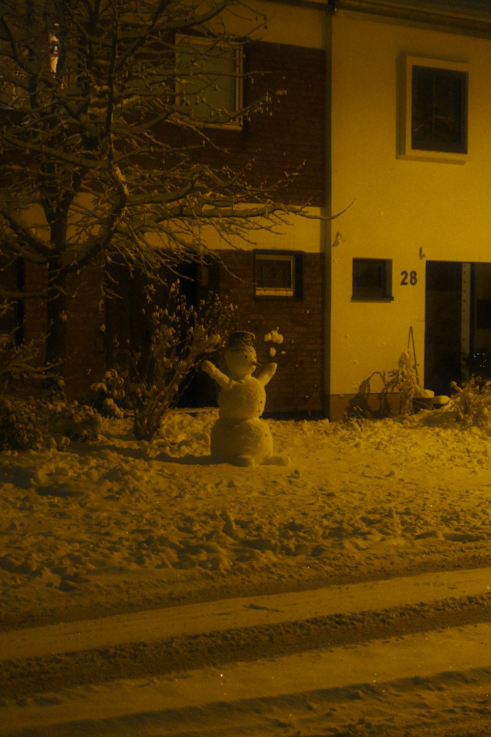 a snowman in front of a house on a snowy night