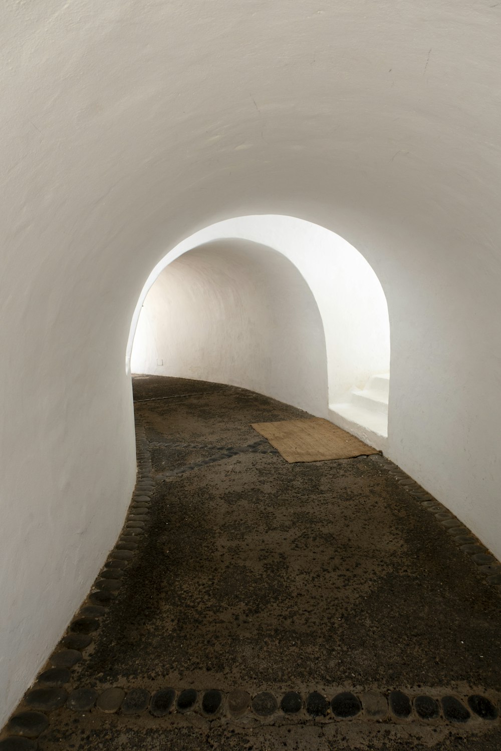 a white tunnel with a bench in the middle of it