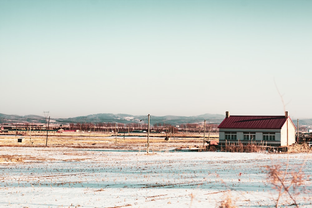 a small white house sitting in the middle of a snow covered field