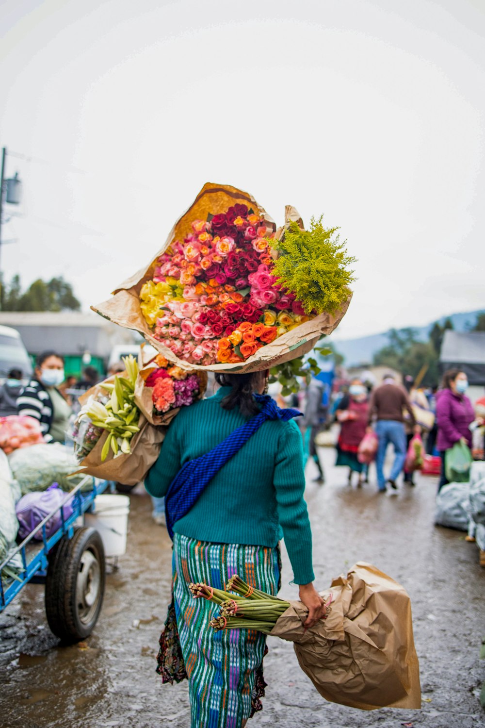 a woman carrying a bunch of flowers on her head