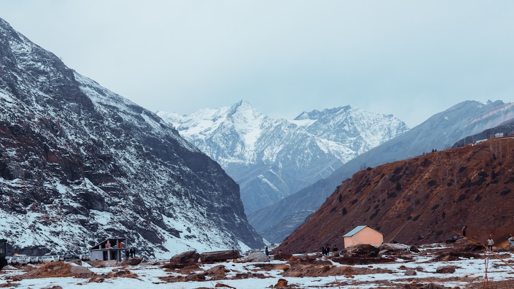 a snow covered mountain range with a house in the foreground