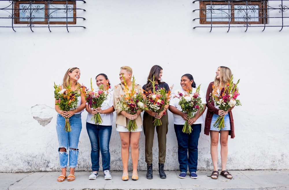 a group of women standing next to each other holding flowers