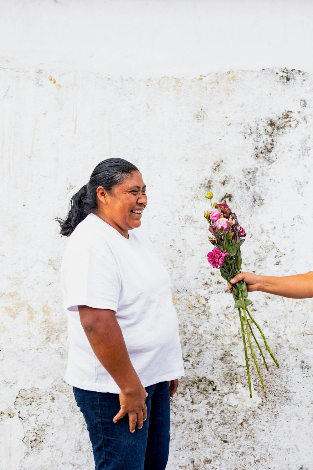 a woman handing a bouquet of flowers to a man